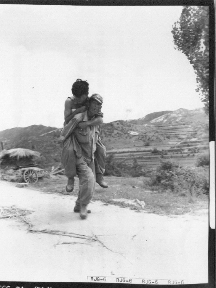 1950. 7. 29. 국군 병사가 뜨거운 전우애로 부상병을 업어 후송시키고 있다.