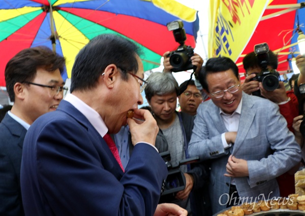 홍준표 자유한국당 대표가 16일 오후 대구 반야월시장을 찾아 '국화빵'을 먹고 김상훈 대구시당위원장이 주머니에서 돈을 꺼내기 위해 손을 집어넣고 있다.