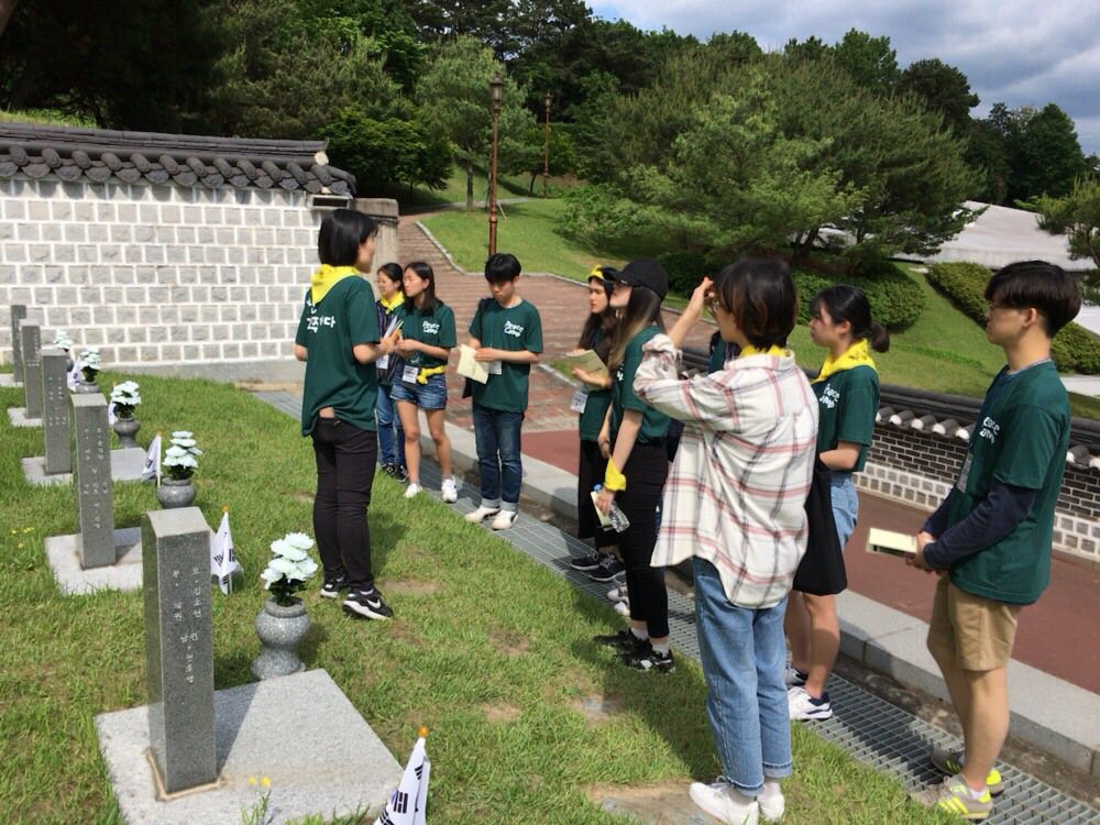  묘역 앞에서 한 참가자가 다른 참가자들에게 묘역 설명을 진행하고 있다