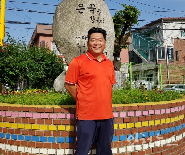 양동열 상인천초등학교 야구부장교사가 교문 입구에서 활짝 웃고 있다.ⓒ 인천뉴스