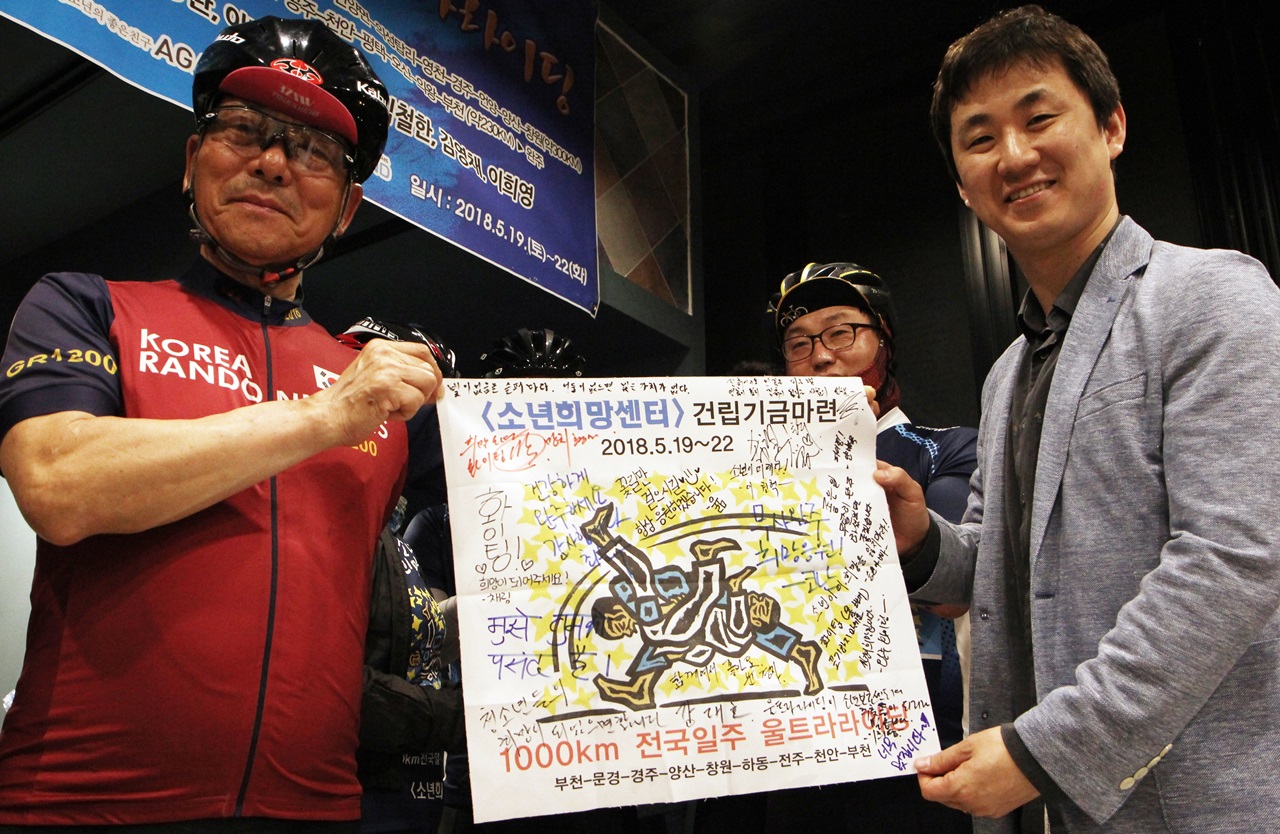 강대호 라이더가 1천km를 함께 질주한 응원 플래카드를 임진성 소년희망센터 건립추진위원장에게 전달했다.