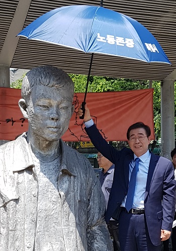 26일 오전 기자회견을 끝낸 더불어민주당 박원순 서울시장 후보가 전태일 열사 동상에 우산을 씌워 주고 있다.