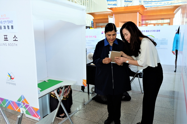 서울시선관위 직원이 아름다운 선거 정보관에서 볼리비아 이주여성에게 투표방법을 안내해 주고 있다.