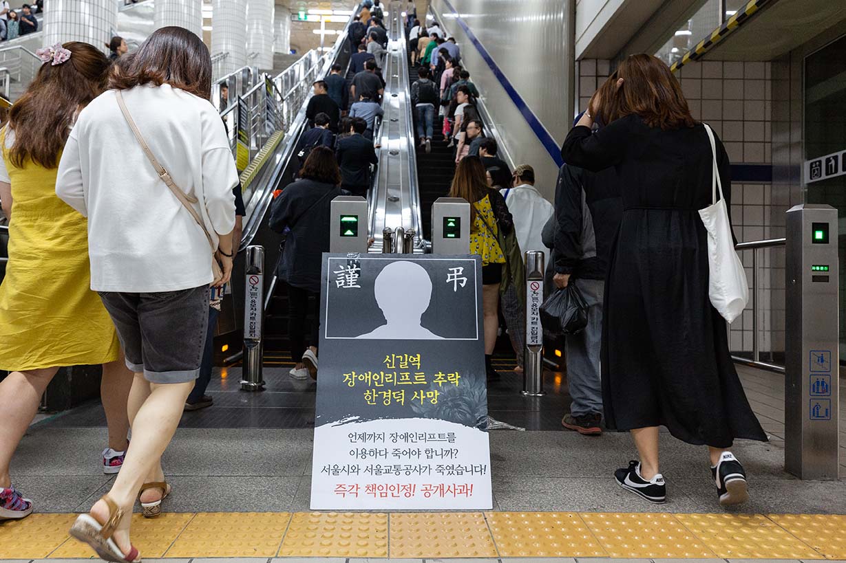 시민들이 서울시에 고 한경덕 씨 사망에 대한 책임 요구하는 팻말 사이로 지나고 있다.