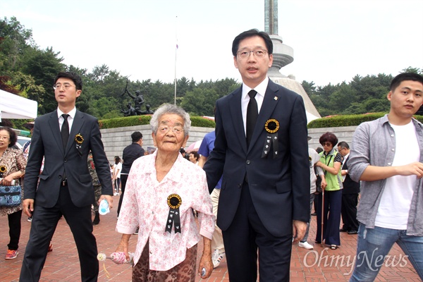 더불어민주당 김경수 경남지사 후보가 6월 6일 오전 창원 충혼탑에서 열린 '제63회 현충일 추념식'에 참석한 뒤 한 할머니와 함께 걸어나오고 있다.