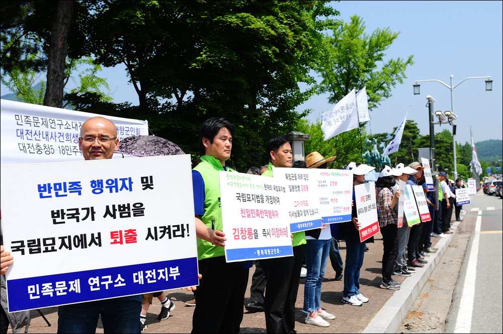 국립묘지법 개정 및 김창룡 묘 이장 촉구대회가 열린 와중, 참가자들이 피켓을 들고 서 있다. 