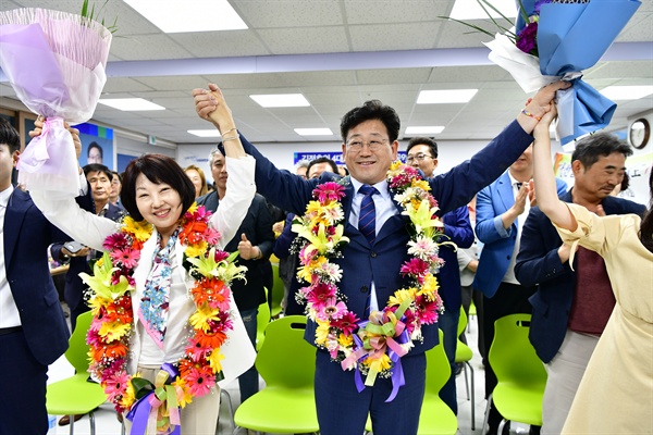 더불어민주당 김정호 '김해을' 국회의원 보궐선거 후보가 당선이 확실시 되자 부인과 함께 꽃다발을 목에 걸고 인사하고 있다.