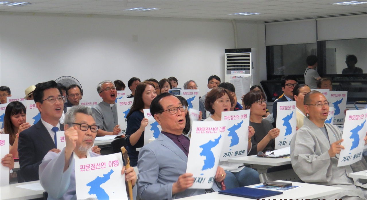 참석자들이 한반도기와 염원이 적힌 종이를 들어보이며 구호를 외치고 있다.  