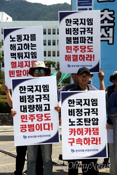 한국지엠 창원공장 비정규직 노동자들이 경남도청 정문 앞에 손팻말을 들고 서 있다.