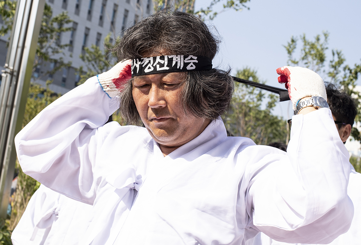 유성기업 노동자들이 20일 오후 대전지방법원 천안지원 일대에서 유시영 회장의 구속을 촉구하는 오체투지 행진에 나선 가운데, 도성대 지회장이 행진에 앞서 머리끈을 동여매고 있다. 