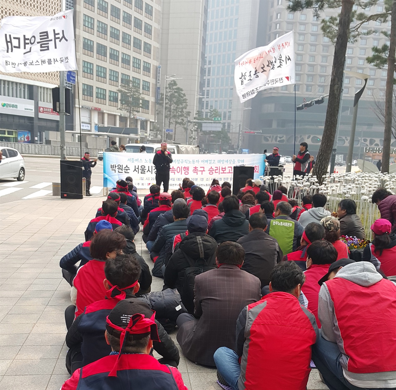 지난 3월 24일 서울시청 앞에서 셔틀버스 노동자들과 서울시 비정규직 노동자들이 모여 박원순 서울시장 약속이행 촉구 투쟁 승리보고 결의대회를 열고 서울시 통학안전 지원센터 올해 설치하기로 합의했다는 면담 결과를 밝히고 있다.