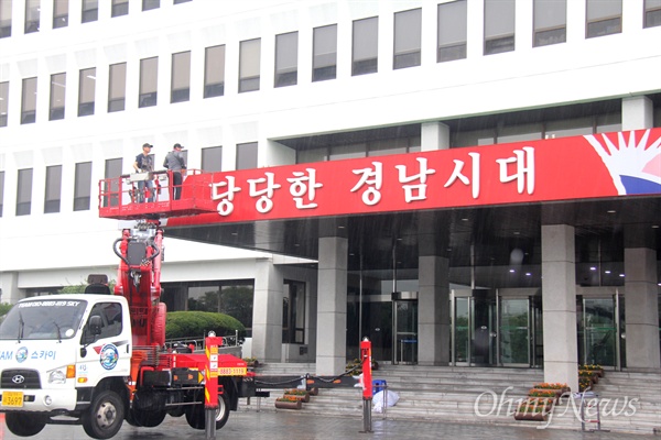  6월 30일 아침 비가 내리는 속에 경남도청 중앙현관에 붙어 있던 '당당한 경남시대' 글자를 철거하는 작업이 진행되고 있다.