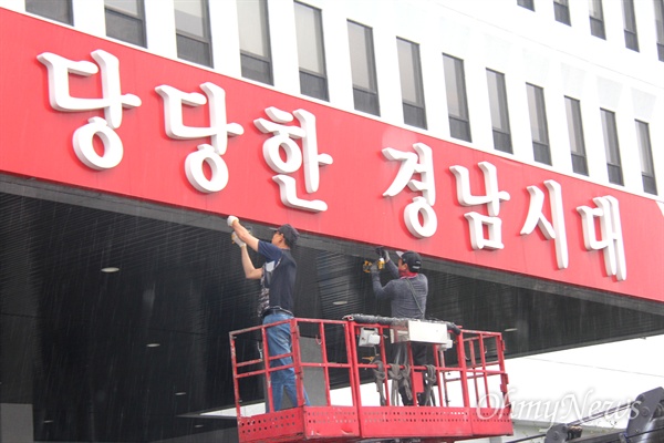  6월 30일 아침 비가 내리는 속에 경남도청 중앙현관에 붙어 있던 '당당한 경남시대' 글자를 철거하는 작업이 진행되고 있다.