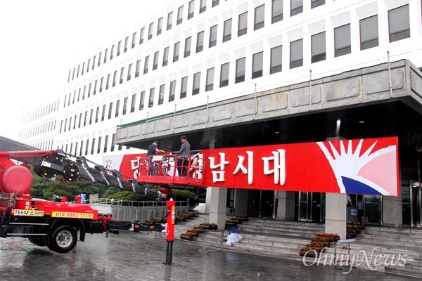  6월 30일 아침 비가 내리는 속에 경남도청 중앙현관에 붙어 있던 '당당한 경남시대' 글자를 철거하는 작업이 진행되고 있다.