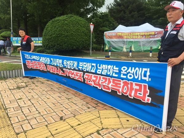 버스기사들이 7월 2일 아침 경남도청 정문 앞에서 펼침막을 들고 서 있다.