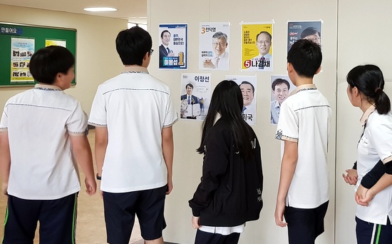 학교 현관 벽에 붙은 교육감 선거 공보를 살펴보는 광주 충장중 학생들. 