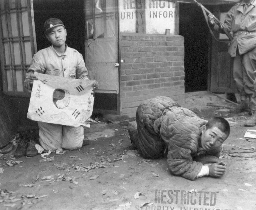 1951. 10. 21. 평양, 한 학생은 자기가 그린 태극기를 들고 살려달라고 애걸하고, 한 인민군은 땅에 엎드려 목숨을 구걸하고 있다.