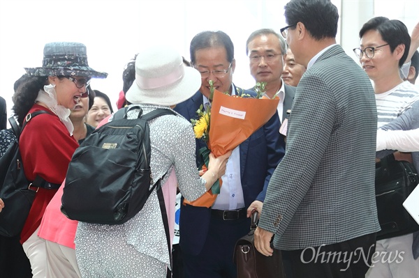 6.13 지방선거 패배의 책임을 지고 물러난 홍준표 전 자유한국당 대표가 11일 오후 인천국제공항 제2여객터미널에서 출국하는 도중 배웅나온 한 지지자로부터 꽃다발을 건네받고 있다.