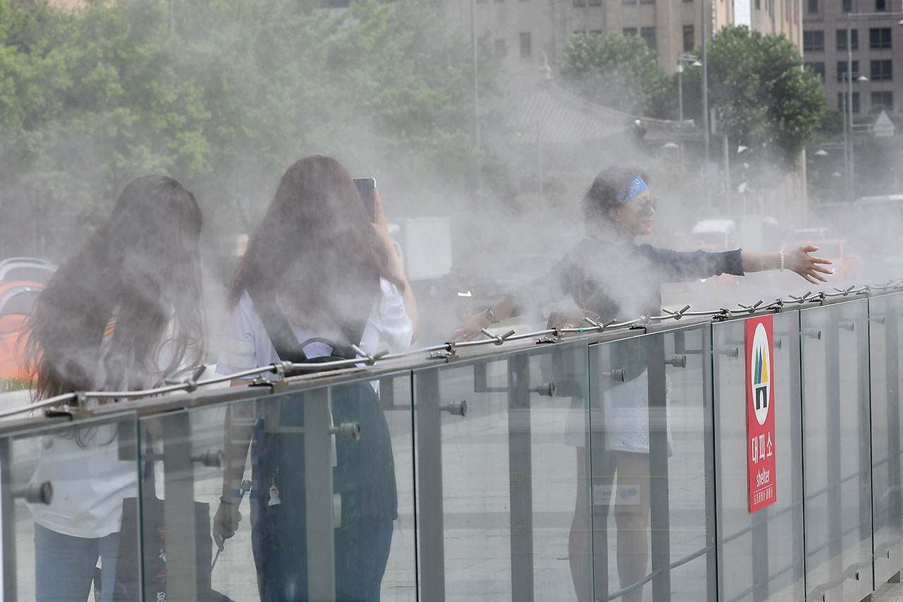 전국 대부분의 지역에서 30도를 웃돌며 찜통더위가 기승을 부리고 있는 가운데 13일 오후 서울시 세종로 광화문광장을 찾은 외국인들이 쿨 스팟 (Cool Spot) 을 맞으며 더위를 식히고 있다. '쿨스팟(Cool Spot)'은 깨끗한 수돗물을 고압으로 분사해 생긴 작은 물방울이 증발하면서 주위의 온도를 2~3도 가량 낮추는 시설이다. 2018.7.13