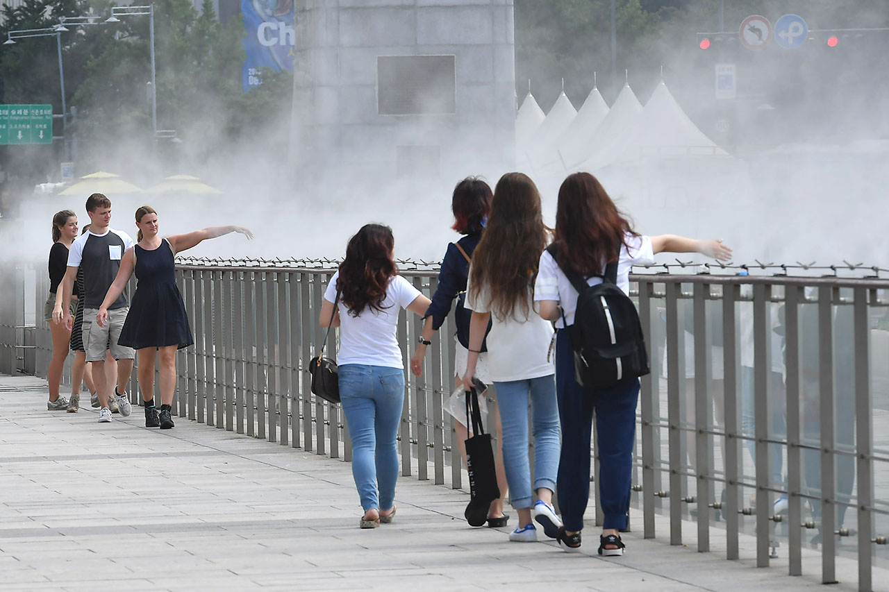 전국 대부분의 지역에서 30도를 웃돌며 찜통더위가 기승을 부리고 있는 가운데 13일 오후 서울시 세종로 광화문광장을 찾은 외국인들이 쿨 스팟 (Cool Spot) 을 맞으며 더위를 식히고 있다. '쿨스팟(Cool Spot)'은 깨끗한 수돗물을 고압으로 분사해 생긴 작은 물방울이 증발하면서 주위의 온도를 2~3도 가량 낮추는 시설이다. 2018.7.13