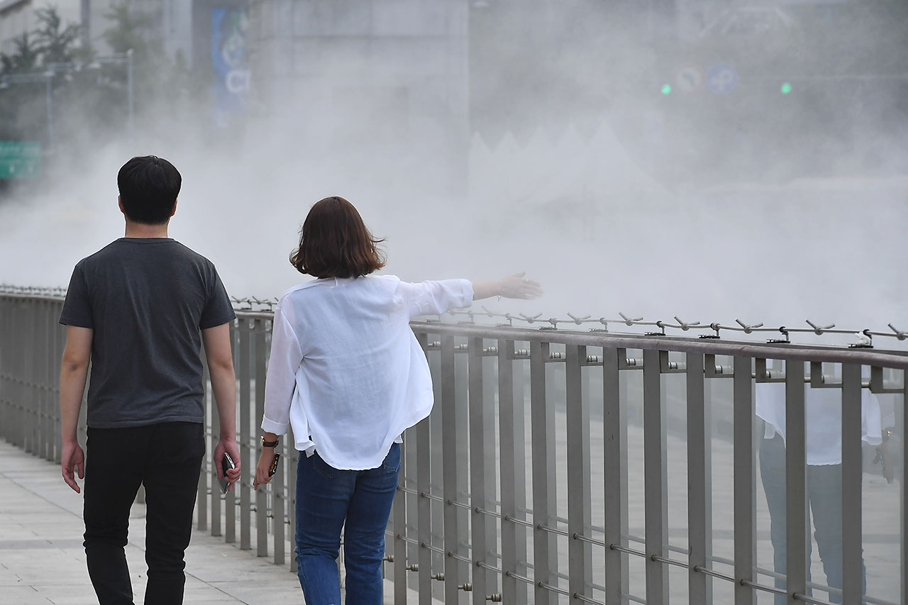 전국 대부분의 지역에서 30도를 웃돌며 찜통더위가 기승을 부리고 있는 가운데 13일 오후 서울시 세종로 광화문광장을 찾은 시민들이 쿨 스팟 (Cool Spot) 옆을 지나가며 더위를 식히고 있다. '쿨스팟(Cool Spot)'은 깨끗한 수돗물을 고압으로 분사해 생긴 작은 물방울이 증발하면서 주위의 온도를 2~3도 가량 낮추는 시설이다. 2018.7.13