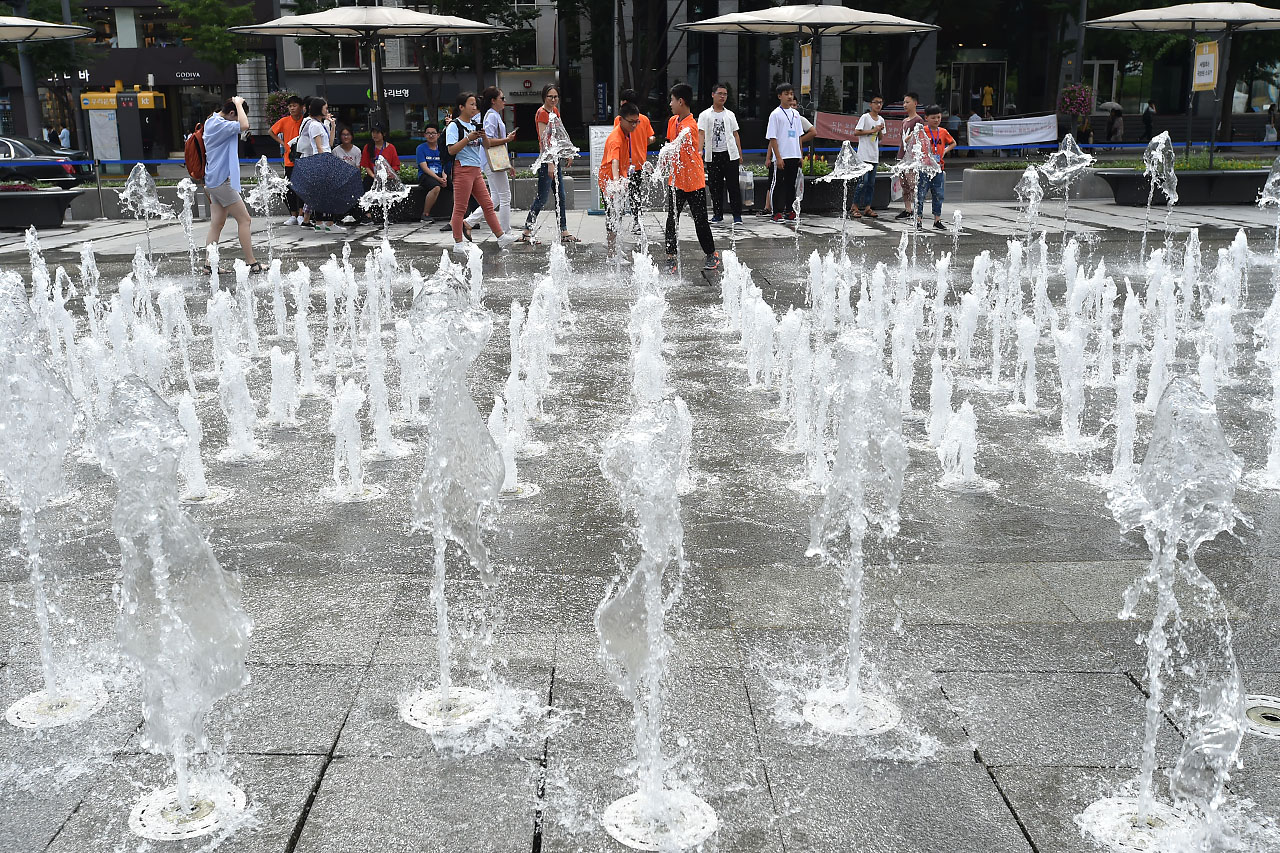 전국 대부분의 지역에서 30도를 웃돌며 찜통더위가 기승을 부리고 있는 가운데 13일 오후 서울 세종로 광화문광장을 찾은 외국인 학생들이 광장 분수대에서 뿜어져 나오는 물을 맞으며 더위를 식히고 있다. 2018.7.13