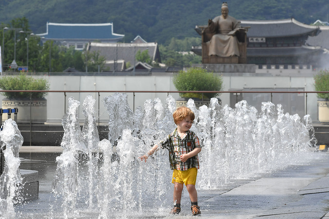 전국 대부분의 지역에서 30도를 웃돌며 찜통더위가 기승을 부리고 있는 가운데 13일 오후 서울 세종로 광화문광장을 찾은 한 외국인 어린이가 광장 분수대에서 뿜어져 나오는 물을 맞으며 더위를 식히고 있다. 2018.7.13