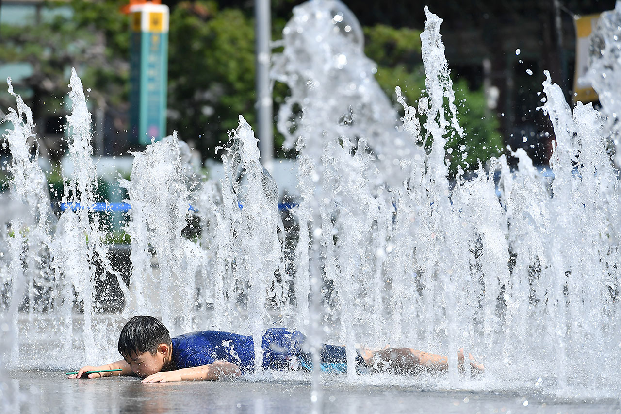 서울에 올 여름들어 처음으로 폭염경보가 발효된 16일 오후 광화문광장을 찾은 한 어린이가 광장 분수대에서 뿜어져 나오는 물줄기 속에 엎드린채 더위를 식히고 있다. 2018.7.16
