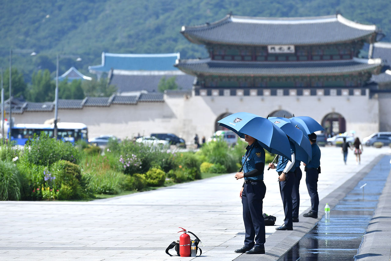  서울에 올 여름들어 처음으로 폭염경보가 발효된 16일 오후 주한미국대사관을 경비하는 경찰들이 뜨겁게 내리쬐는 햇빛을 가리기 위해 우산을 쓴채 경계근무를 서고 있다.  2018.7.16