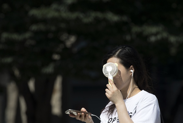  폭염이 이어지고 있는 17일 오전 서울 세종로사거리에서 한 시민이 휴대용 선풍기로 더위를 식히고 있다.