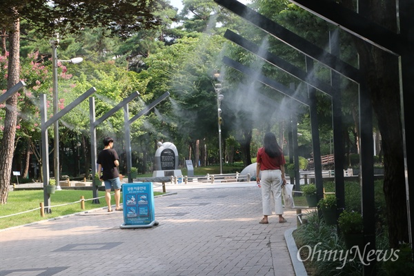 대구 2.28기념공원에서 한 시민이 설치된 쿨링포그에서 뿜어져 나오는 물분자를 맞으며 더위를 피하고 있다.