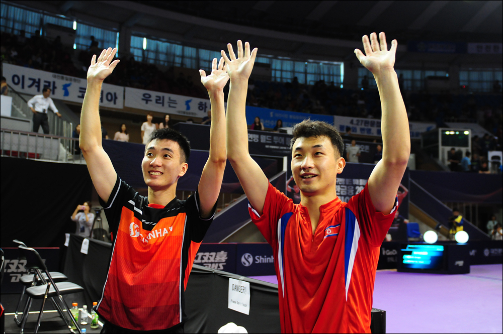  남북 단일팀의 이상수(왼쪽), 박신혁(오른쪽) 선수가 남자 복식 8강전에서 승리한 후 응원석을 향해 손을 번쩍 들고 있다.