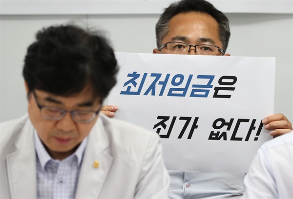  23일 오후 서울 영등포구 한국중소상인자영업자총연합회 사무실에서 열린 최저임금 인상 입장 발표 기자회견에서 한 참석자가 손팻말을 들고 있다. 