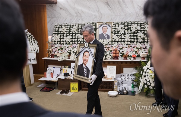  26일 오전 서울 서대문구 신촌세브란스병원 장례식장에 마련된 고 노회찬 정의당 원내대표의 빈소에서 김영훈 정의당 노동이당당한나라 본부장이 노 의원 영정을 안고 나오고 있다. 영정은 노 의원의 지역구인 창원으로 향한다.