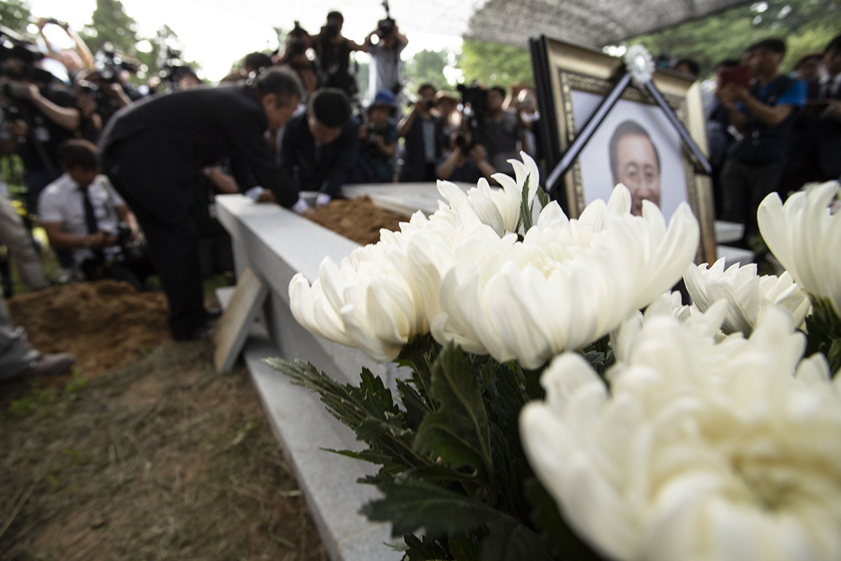 27일 오후 경기도 남양주시 모란공원에서 고 노회찬 정의당 원내대표의 하관식이 열린 가운데 고인의 친동생인 노회건씨가 고인의 유골을 묘소로 옮기고 있다. 