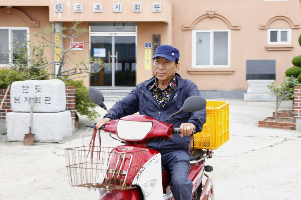 김영복 무안 탄도마을 이장이 오토바이를 타고 마을회관 앞을 지나고 있다. 김 이장은 올해 44년째 이장을 맡고 있다. 전국 최장수 이장이다.