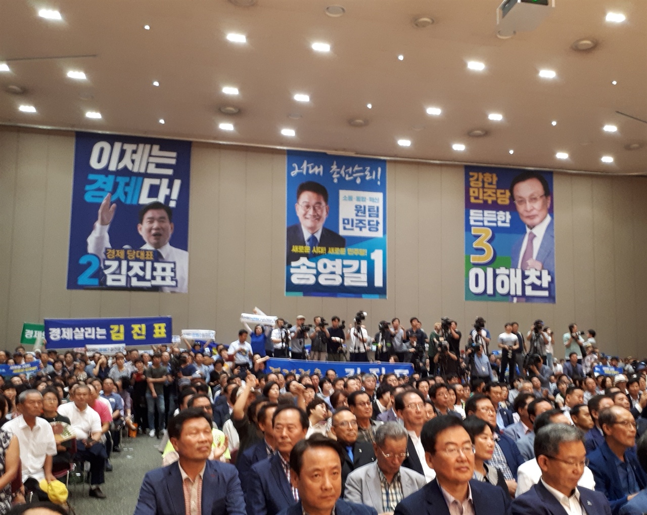4일 광주 김대중컨벤션센터에서 열린 민주당 전당대회에 참석한 이들의 모습이다. 벽면에 당 대표 후보자 세 명의 포스터가 부착되어 있다.