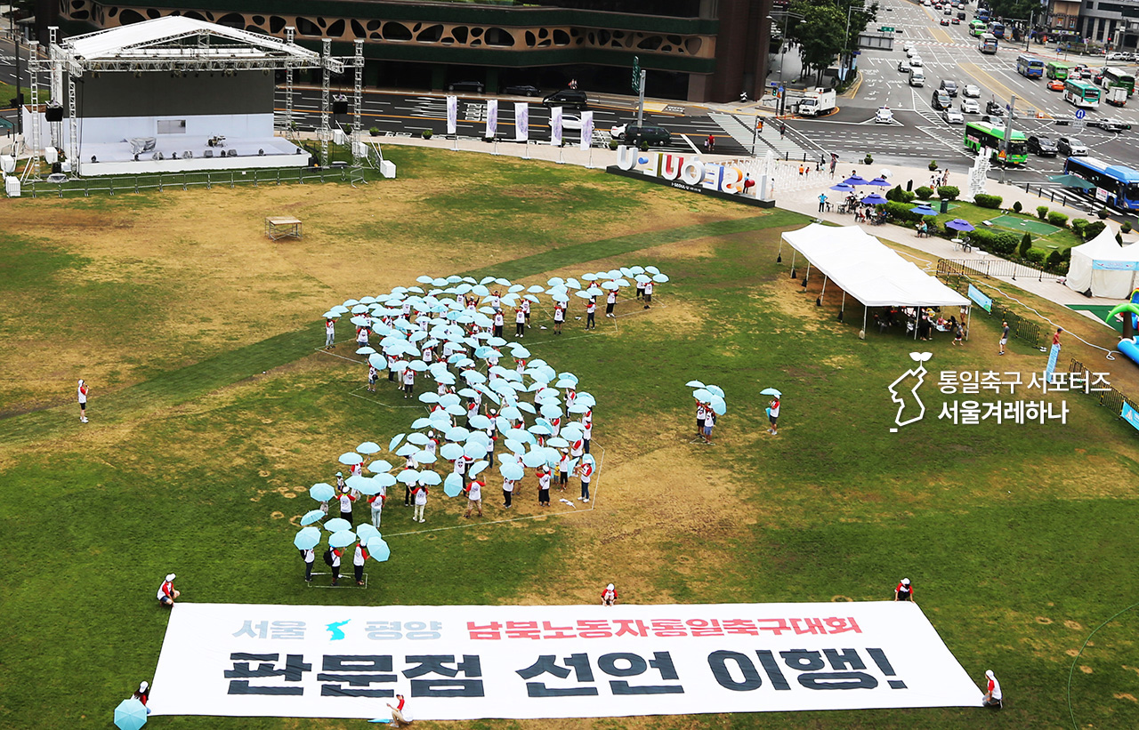  통일축구 서포터즈들은 하늘색 우산을 이용해 서울시청광장에 대형 한반도를 만들었다