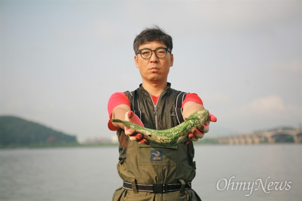 김동언 서울환경운동연합 한강담당 활동가가 한강 녹조의 실상을 알리기 위해 죽은 물고기를 손에 들었다.