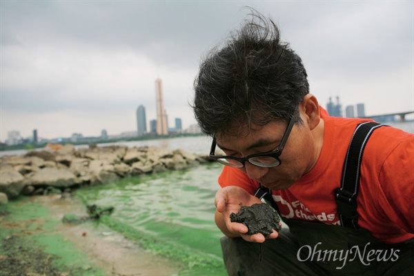 63빌딩 맞은편 한강에서 퍼 올린 시커먼 펄의 냄새를 맡아보고 있는 김동언 서울환경운동연합 활동가