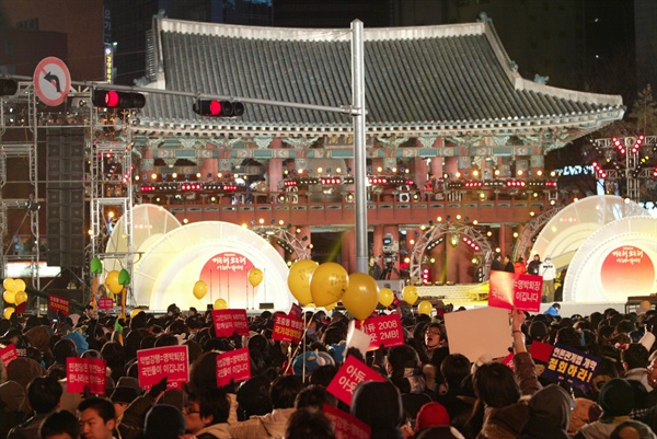 31일 밤 새해 보신각 타종식이 열리는 서울 종각 네거리에 모인 시민들이 '이명박 퇴진' '아듀 2008 아듀 MB!' '언론관계법 개악 철회하라' 등의 구호가 적힌 종이피켓과 '선생님을 돌려주세요'가 적힌 노란풍선을 들고 있다.
