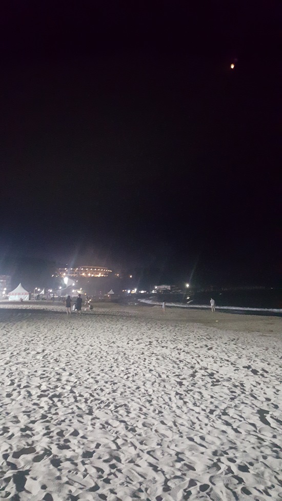밤의 낙산해변의 모래와 파도. 밤하늘의 달처럼 보이는 건 관광객이 띄운 등불이다. 