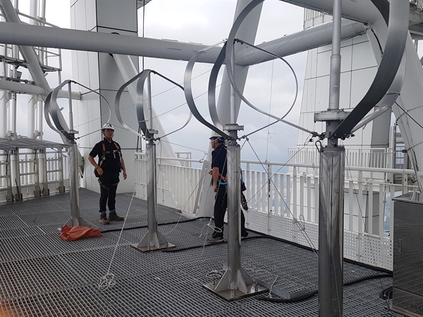 롯데월드타워 최상층부 랜턴구간에 설치된 풍력발전기에 작업자가 와이어 고정 작업을 하고있다.