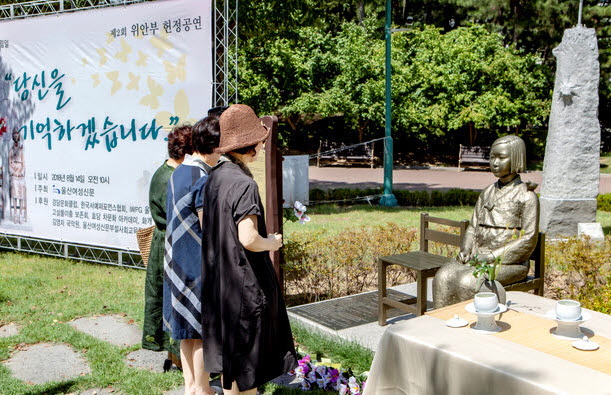 8월 14일 울산 남구 신정동 울산대공원 동문 광장 입구에 있는 '평화의 소녀상'앞에서 열린 위안부 기림 행사에서 참석자들이 헌화하고 있다 