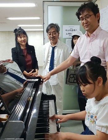 개인 레슨 공연이 끝나고 초등학생으로 보이는 한 어린이가 전문가 지도 하에 무료 피아노 레슨을 받고 있다.