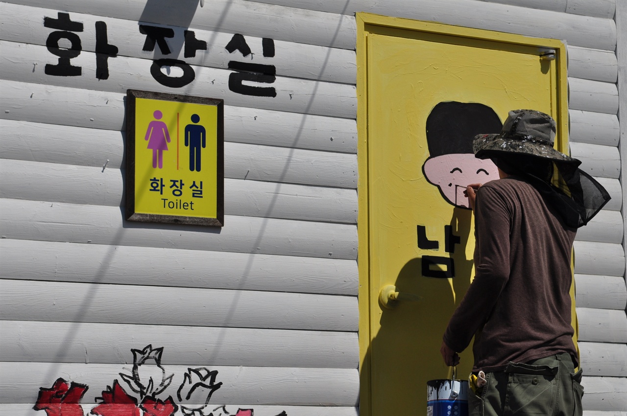 어떤 참가자가 화장실 앞에서 남자와 여자를 구분하는 그림을 그리고 있다. 