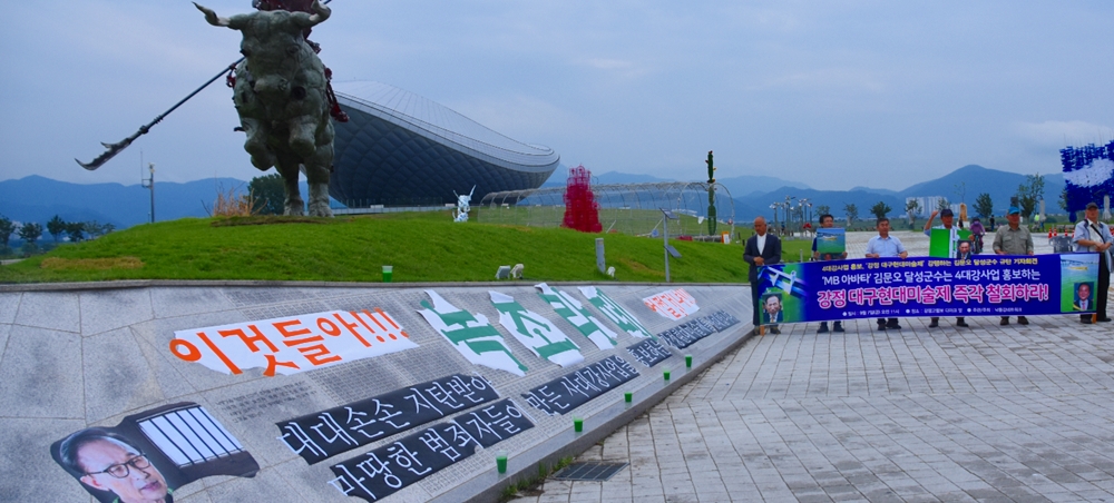 "이것들아 녹조라떼 어쩔거냐?"라는 문구를 붙인 4대강 기념비 앞에서 강정 대구현대미술제 반대 집회를 벌이고 있다. 