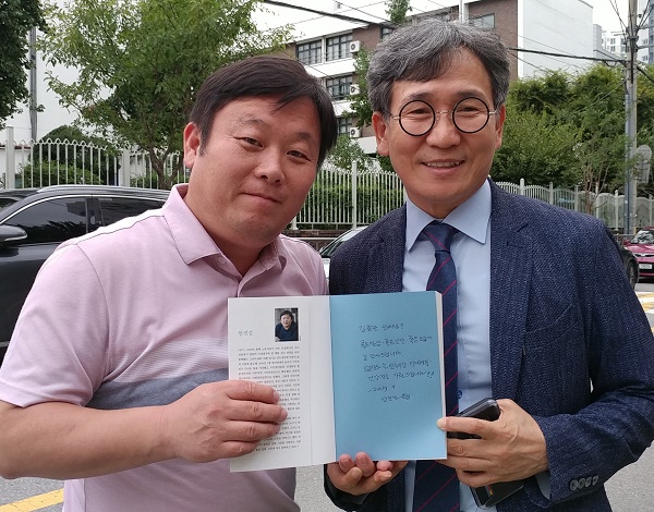 지난 15일 오후 저자인 안진걸 민생경제연구소장이 친필을 한 책을 주면서 기자와 함께 기념사진을 촬영했다.