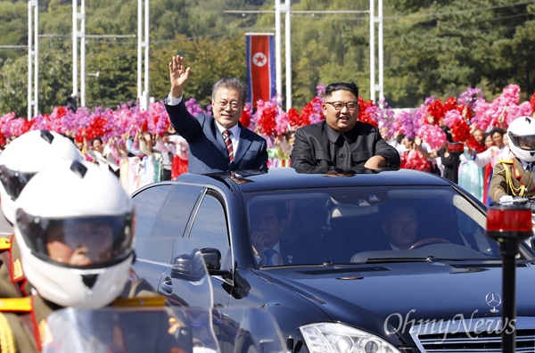 18일 남북정상회담을 위해 평양에 도착한 문재인 대통령이 김정은 국무위원장과 함께 무개차를 타고 평양시내로 이동하며, 환영하는 주민들을 향해 손을 흔들며 인사하고 있다.