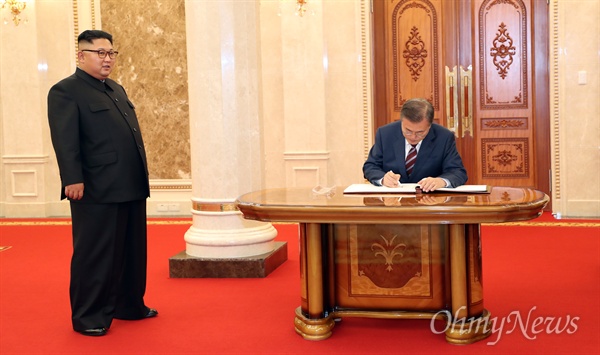 2018년 9월 18일, 문재인 대통령이 평양 조선노동당 중앙위원회 본부 청사에서 김정은 국무위원장이 지켜보는 가운데 방명록에 서명하고 있는 모습. 